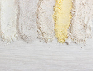 Different types of flour on wooden table, top view