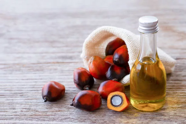 Palm oil in glass bottle and fresh oil palm fruit on wooden table background.